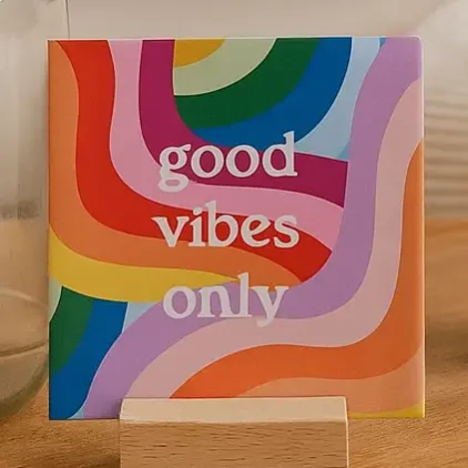 Quadratische Keramikfliese mit buntem Wellenmuster in Regenbogenfarben und weißem Text „good vibes only