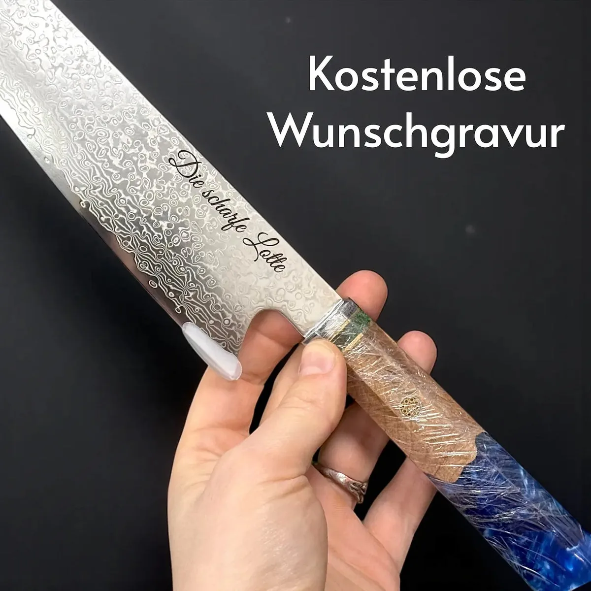 Damastmesser Umi in Hand, Klinge mit feinem Wellenmuster und Gravur sichtbar, blauer Kunstharzgriff mit Ahornwurzel.