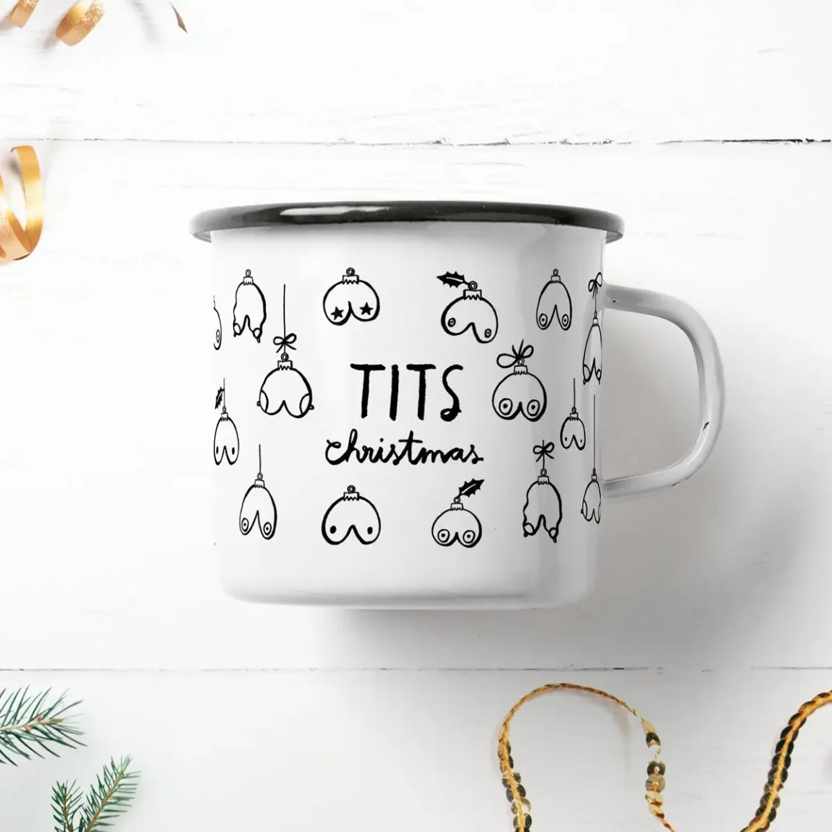 Weiße Emailletasse mit schwarzem Rand und Henkel, bedruckt mit Brustmotiven als Weihnachtskugeln und Schriftzug „TITS…