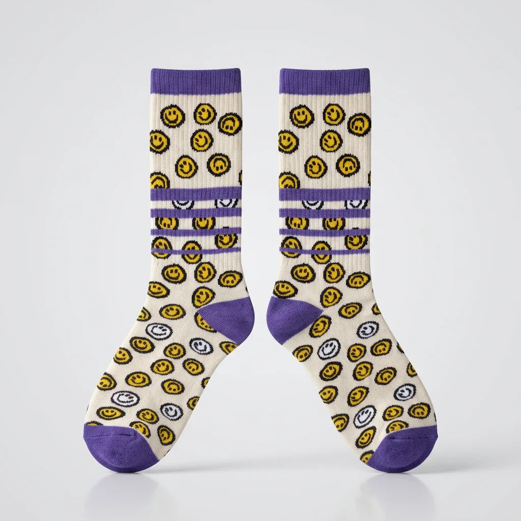 Zwei Sportsocken nebeneinander, lila-weiß mit gelben und weißen Smiley-Motiven, lila Ferse und Schaft.