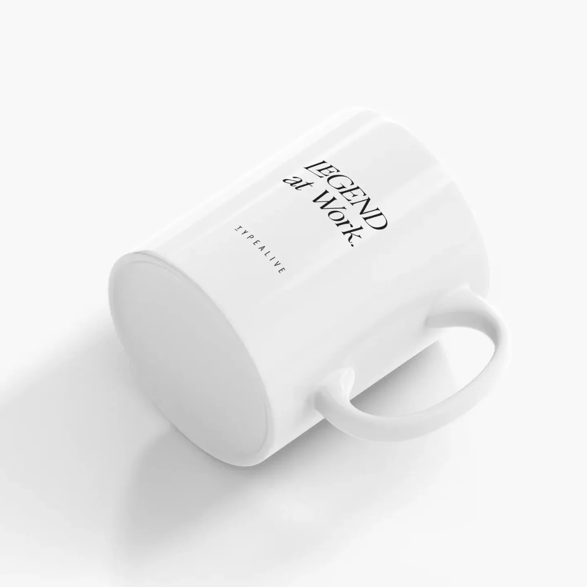 Weiße Keramiktasse von der Seite, schwarzer Text diagonal angeordnet: „LEGEND AT WORK