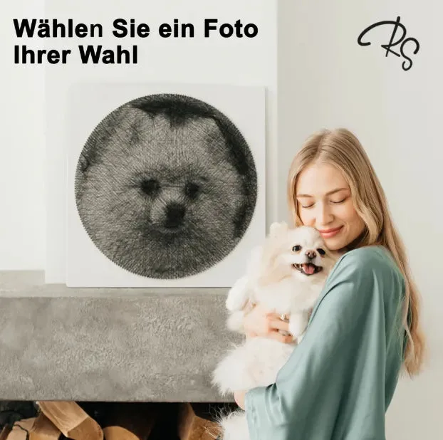 Frau mit weißem Hund hält das fertige String-Art-Werk in den Händen – ein Porträt des Hundes aus schwarzem Faden auf weißer…
