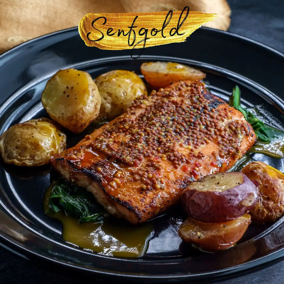 Senfkaviar auf gegrilltem Fischfilet mit Kartoffeln und Gemüse auf dunklem Teller, goldgelbe Körner sichtbar.