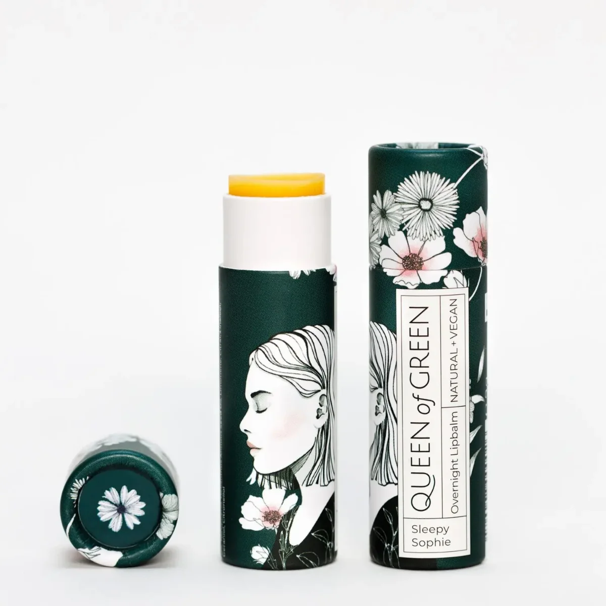 Lippenpflege-Stift nacht, Queen of Green: Stift mit gelblicher Pflegemasse, daneben liegende dunkelgrüne Kartonhülse mit…