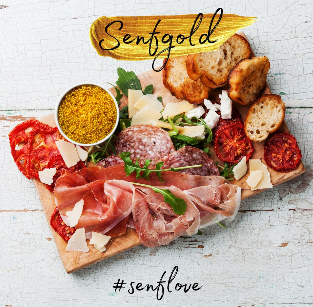 Senfgold Curry in einer weißen Schale, umgeben von Schinken, Salami, Käse, Tomaten und Brotscheiben auf Holzbrett.
