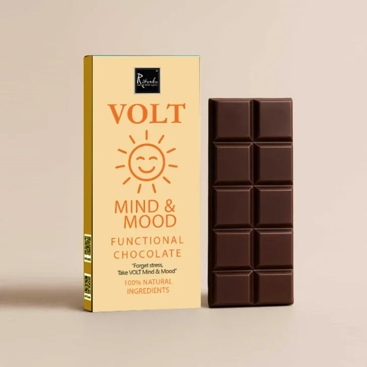 Schokolade mit Safran: Creme-weiße Verpackung mit orangem VOLT-Logo und aufgebrochene dunkle Schokoladentafel daneben.