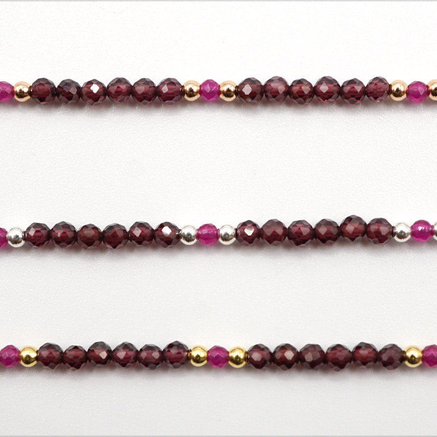 Drei Reihen facettierter Granat- und Rubin-Perlen in Dunkelrot und Magenta, unterbrochen durch kleine glänzende…