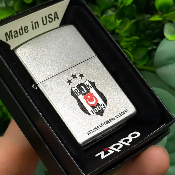 Silbernes Zippo Feuerzeug mit graviertem Wappen-Logo in schwarzer Originalverpackung, von oben fotografiert.
