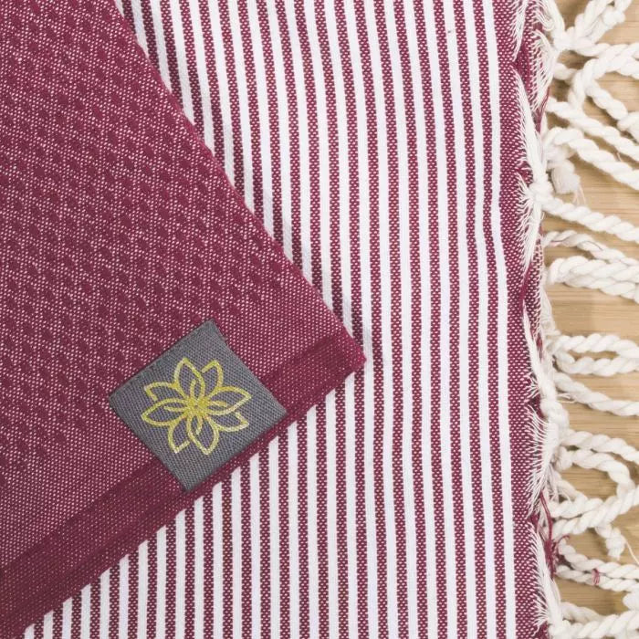 Bordeauxrotes Fouta-Tuch mit feinen weißen Streifen, Wabenmuster sichtbar, Jasmin-Logo-Label eingewebt, geflochtene weiße…