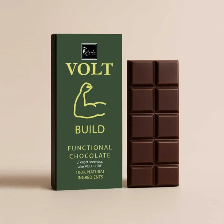 Schokolade mit Magnesium: grüne Verpackung mit gelbem VOLT-Build-Logo neben aufgebrochener Tafel dunkler Schokolade in…