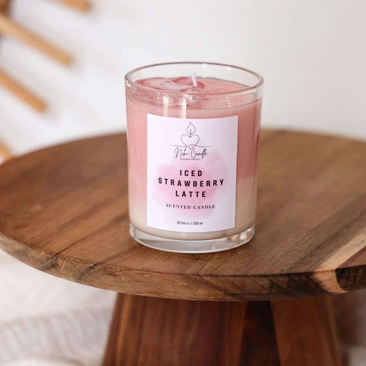 Duftkerze Erdbeer Latte in Glasgefäß mit rosa Wachs und Eiswürfeln, auf Holztablett, Label von Niki Candle sichtbar