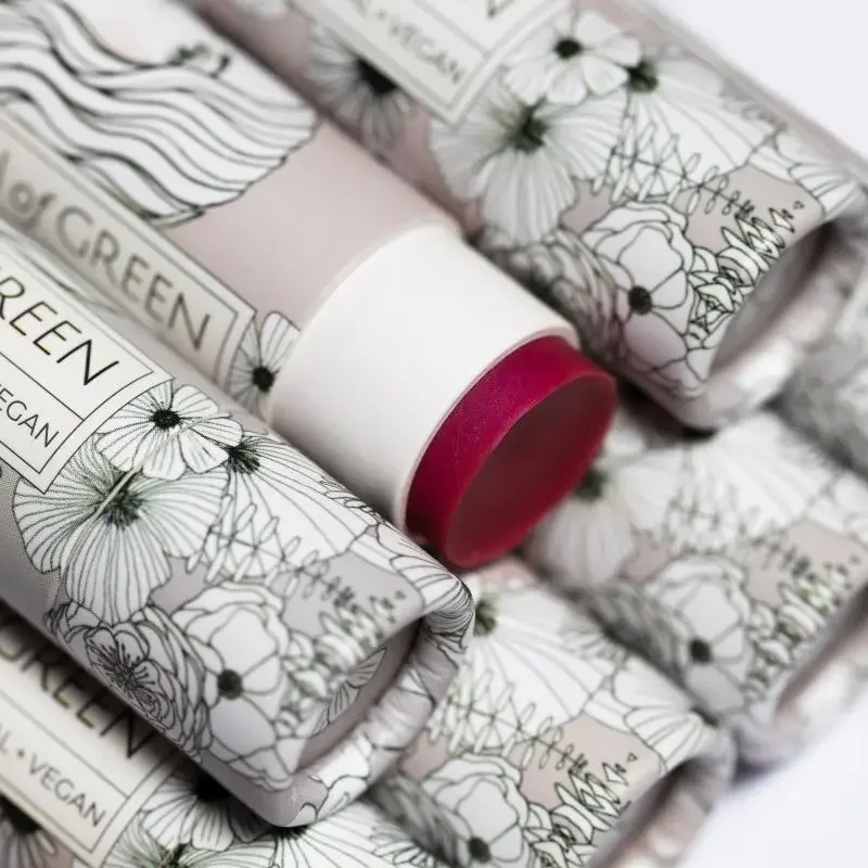 Mehrere Lippenbalsam-Stifte in grau-weißen Kartonhüllen mit Blumenzeichnungen; ein Stift ist halb herausgeschoben und zeigt…