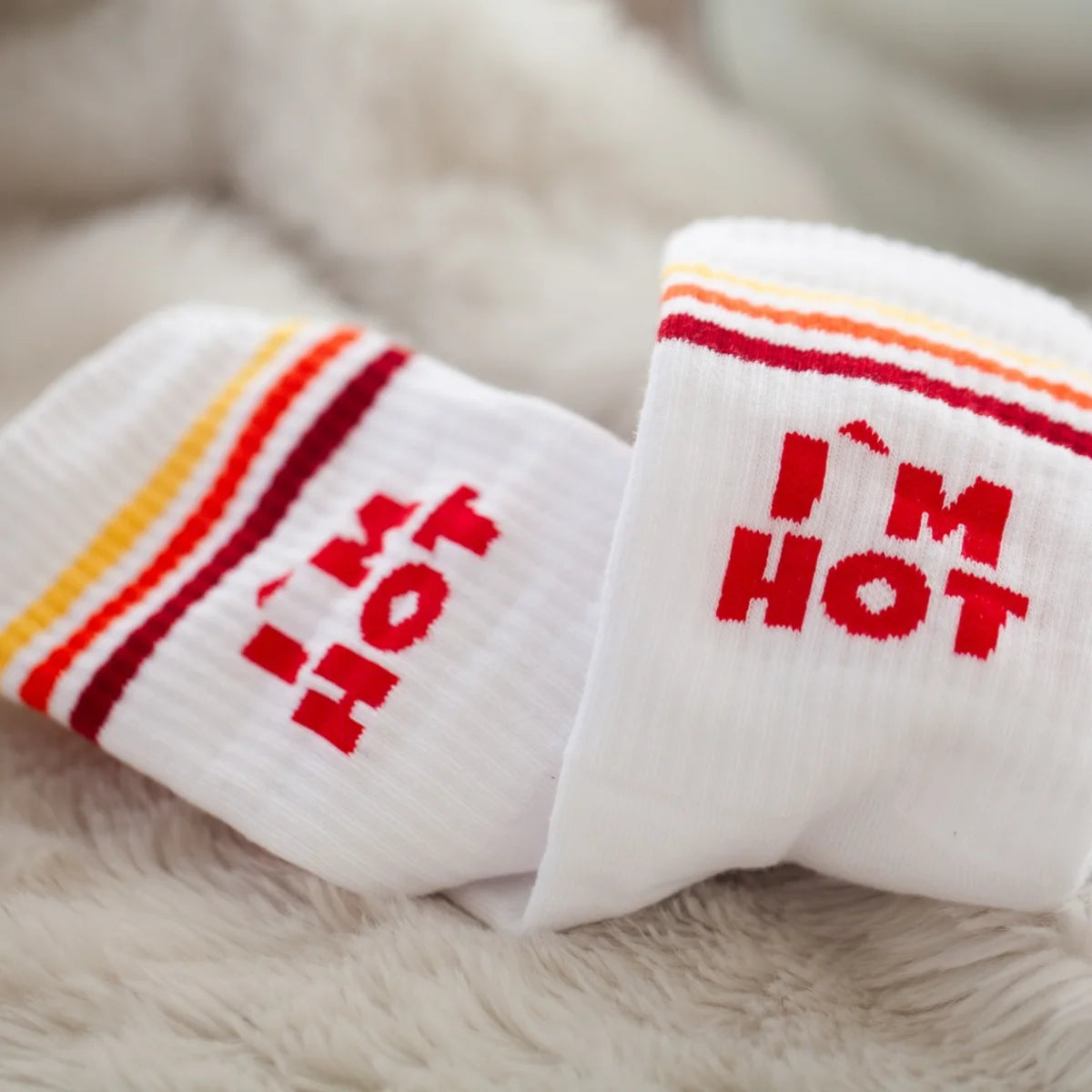 Zwei weiße Sportsocken nebeneinander, rote Schrift „I'M HOT