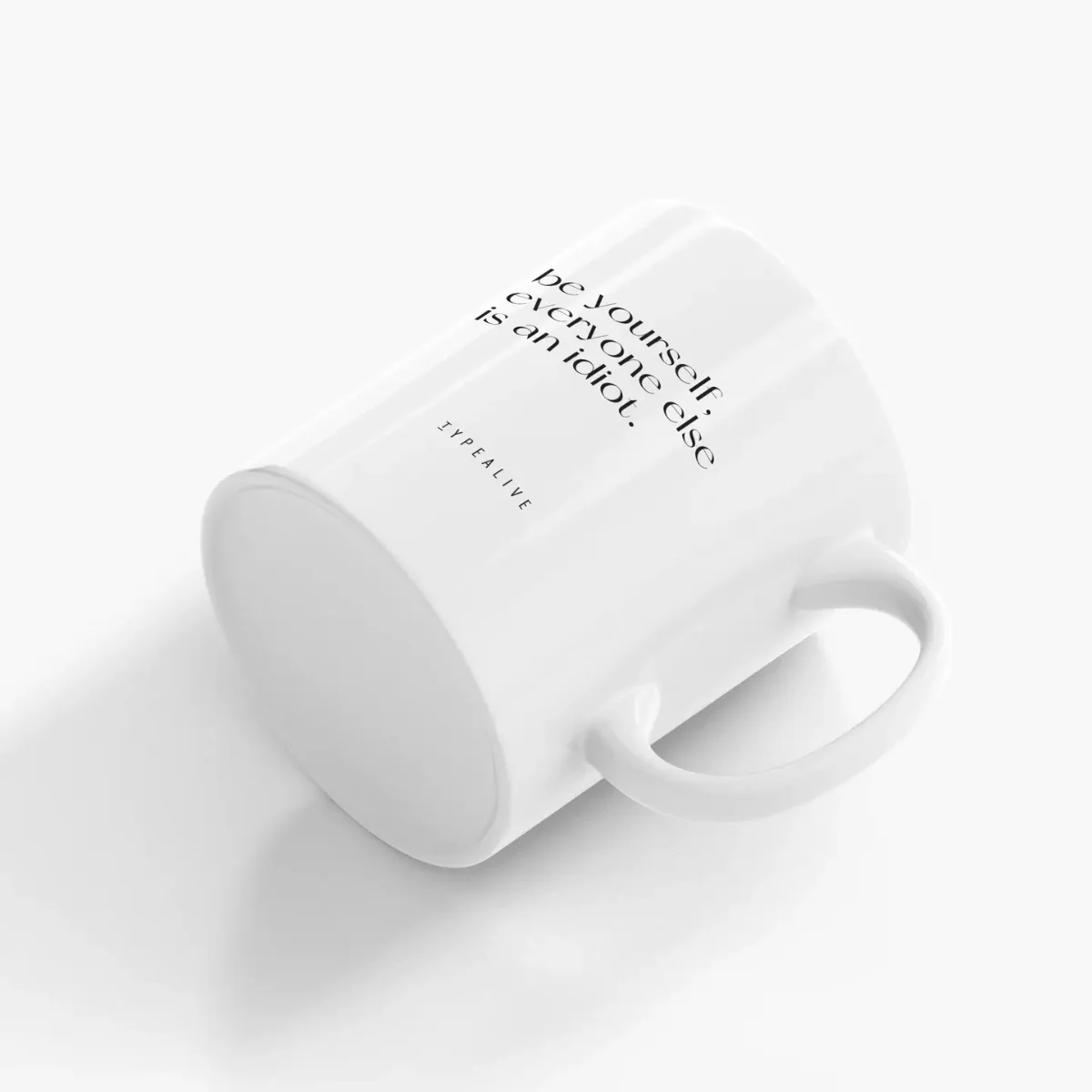 Weiße Keramiktasse von schräg oben, schwarzer Text „Be Yourself