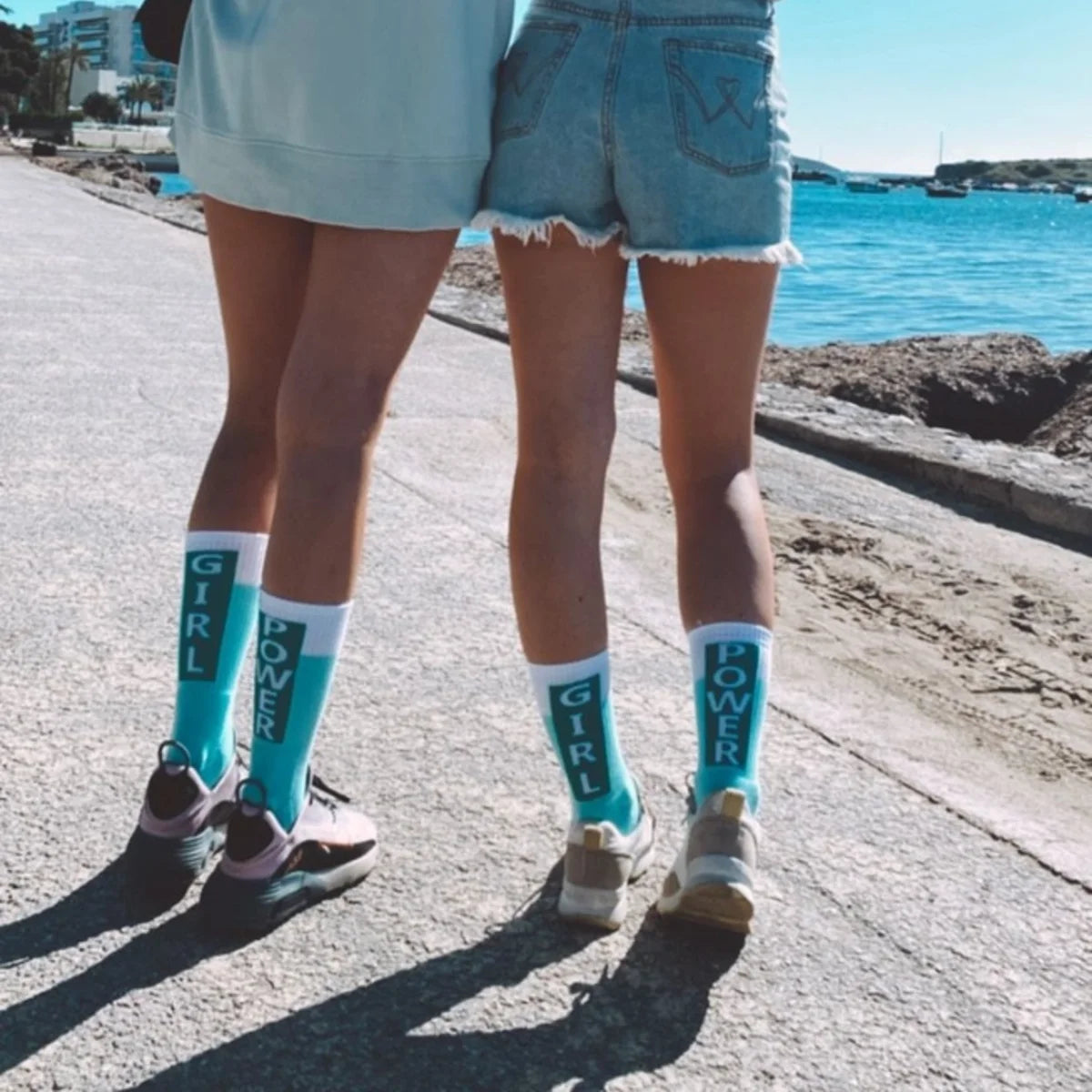 Zwei Personen tragen hellblaue Sportsocken mit „Girl Power