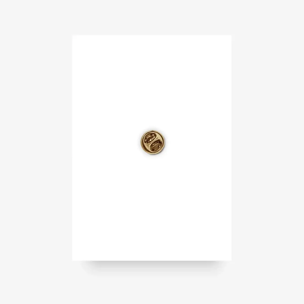 Goldene Anstecknadel mit Mittelfinger-Motiv, Nahaufnahme auf weißem Grund