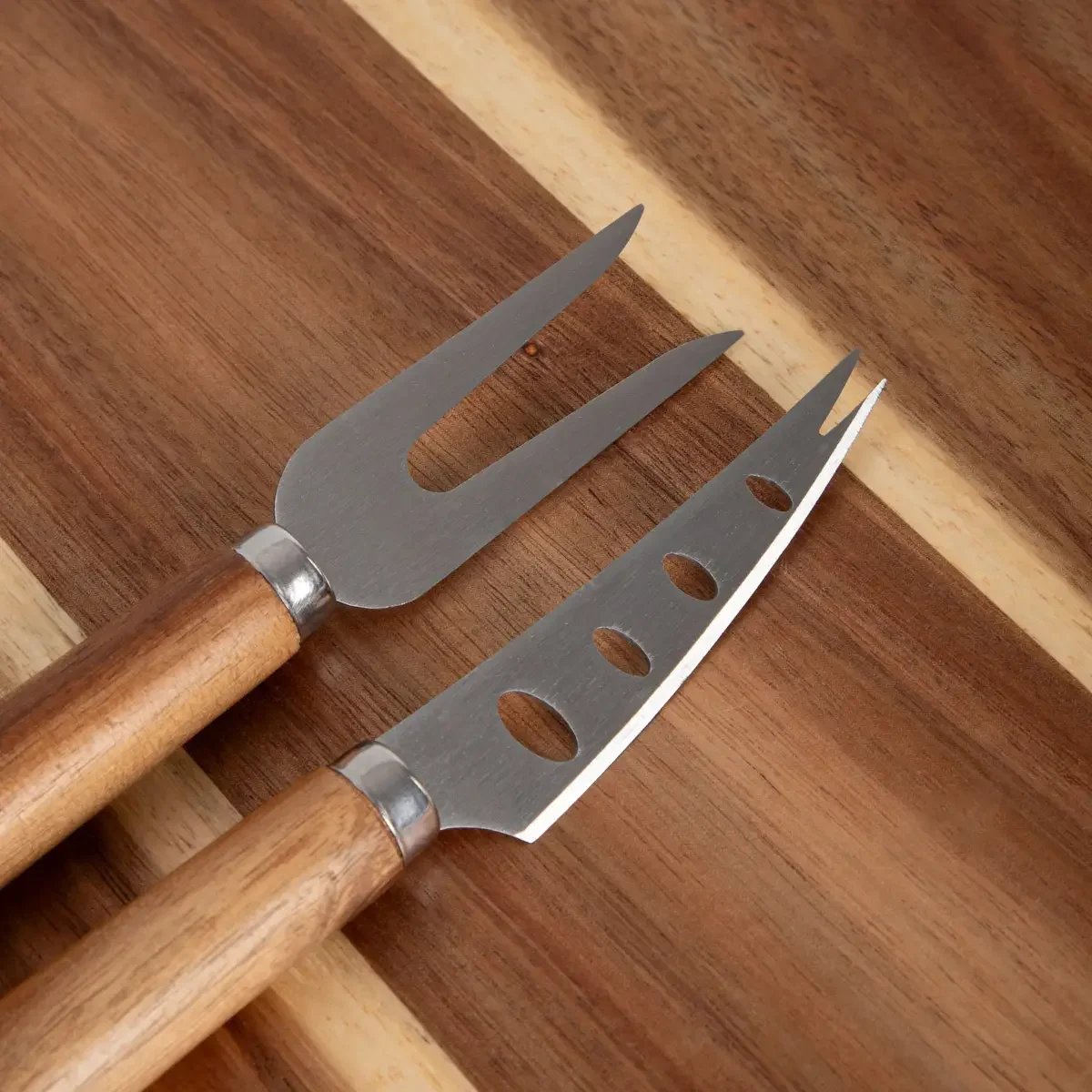 Zwei Edelstahlmesser mit Holzgriffen auf dem Naturholzbrett, Draufsicht.