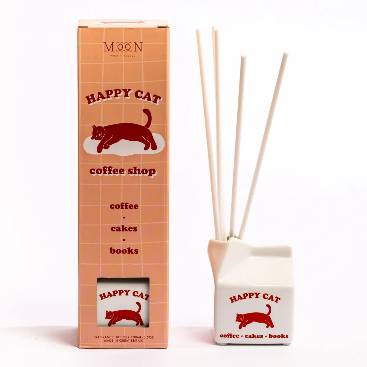 Raumduft Diffuser Happy Cat: Keramik-Milchkarton in Orange-Weiß mit roter Katze, daneben die weiße Keramikflasche mit drei…