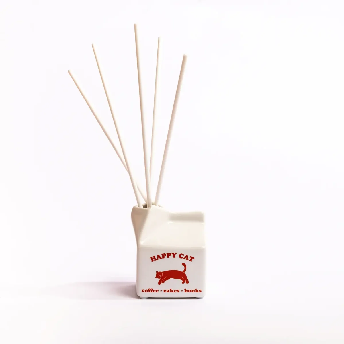 Keramik-Diffuser in Milchkarton-Form, weiß mit rotem Katzenmotiv und Text, fünf helle Diffusorstäbchen oben eingefügt