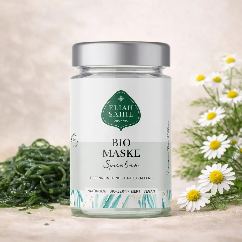 Gesichtsmaske Spirulina von Eliah Sahil in Glasgefäß mit Silberdeckel, umgeben von Spirulina-Algen und Kamillenblüten