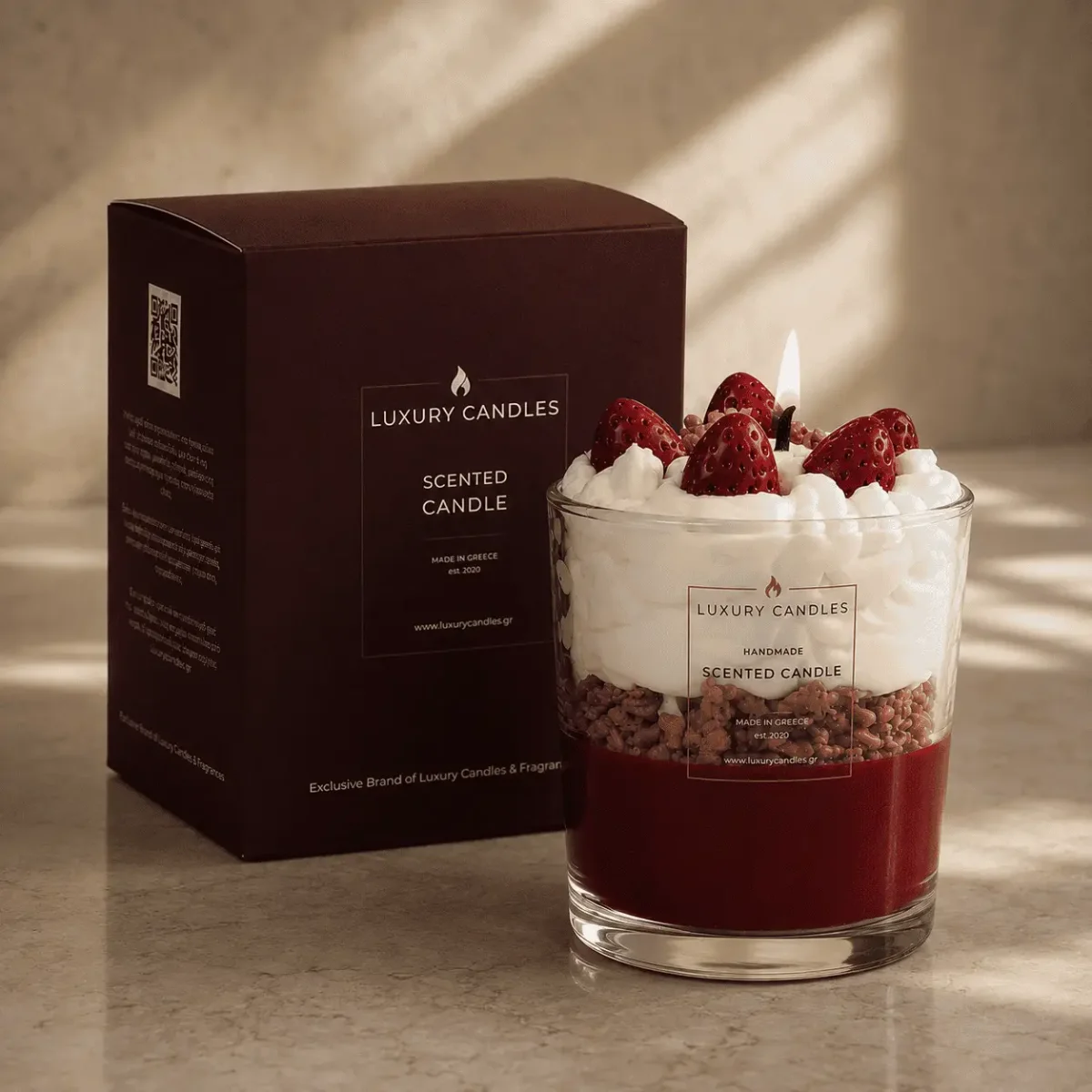 Duftkerze im Glas mit rotem Wachs, weißer Wachsschicht und roten Erdbeeren oben, daneben dunkelrote Verpackungsbox