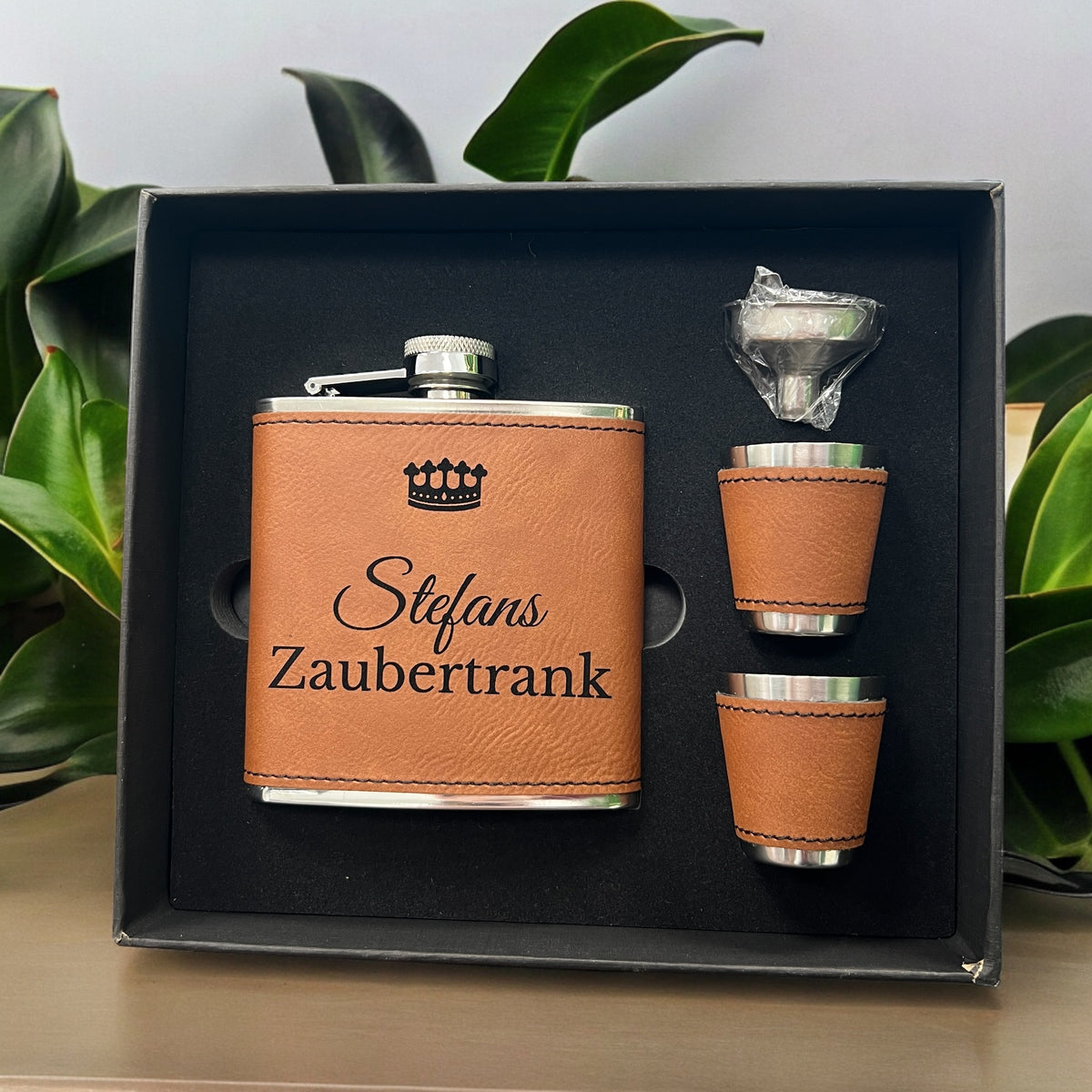 Flachmannset in offener schwarzer Schachtel: brauner Flachmann mit Gravur „Stefans Zaubertrank